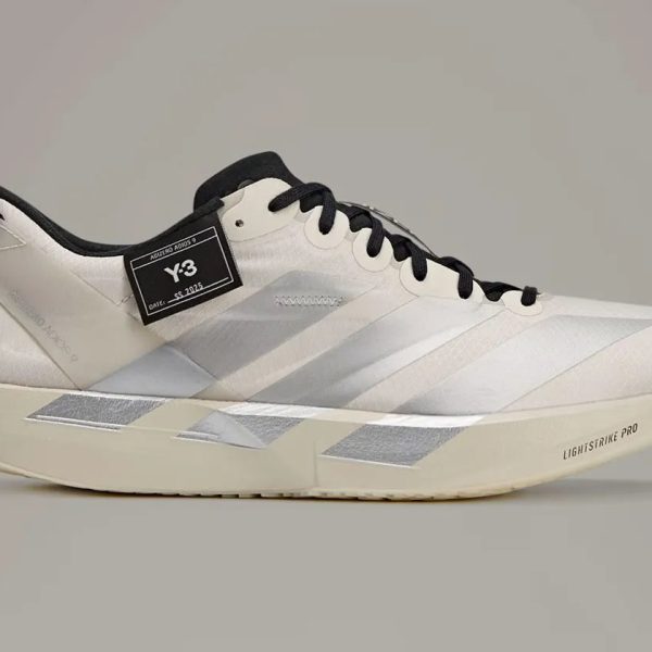 White sneaker with black laces and a black Y-3 tag on the side, featuring light gray chevron stripes and a cream sole marked LIGHTSTRIKE PRO.
