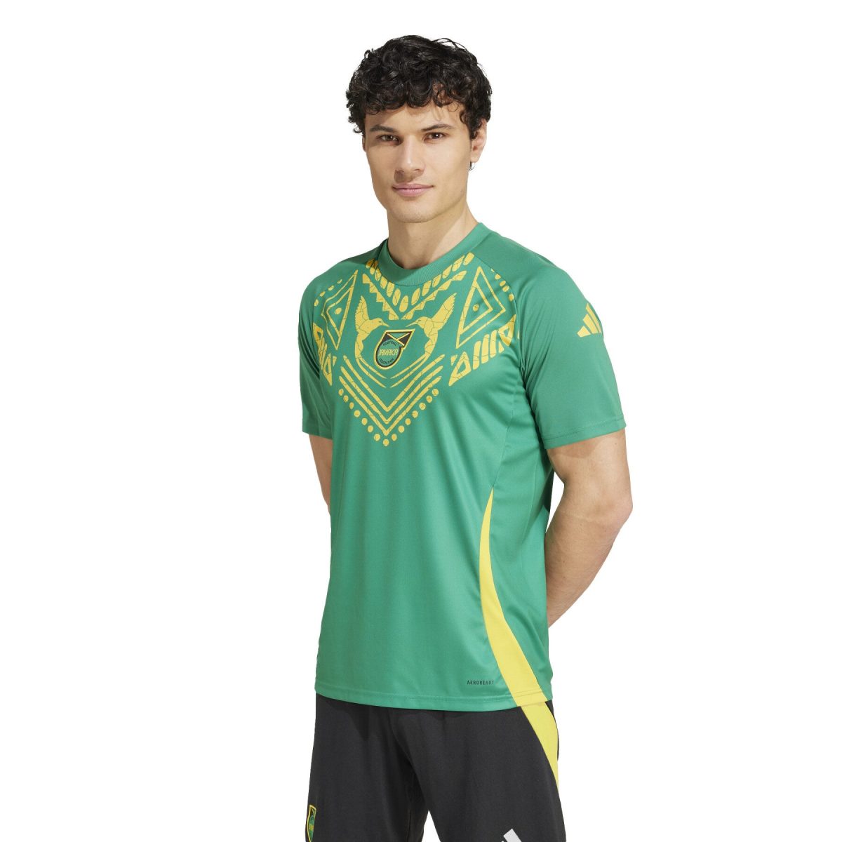 Young man wearing a green athletic jersey with a gold geometric pattern, standing against a white background.