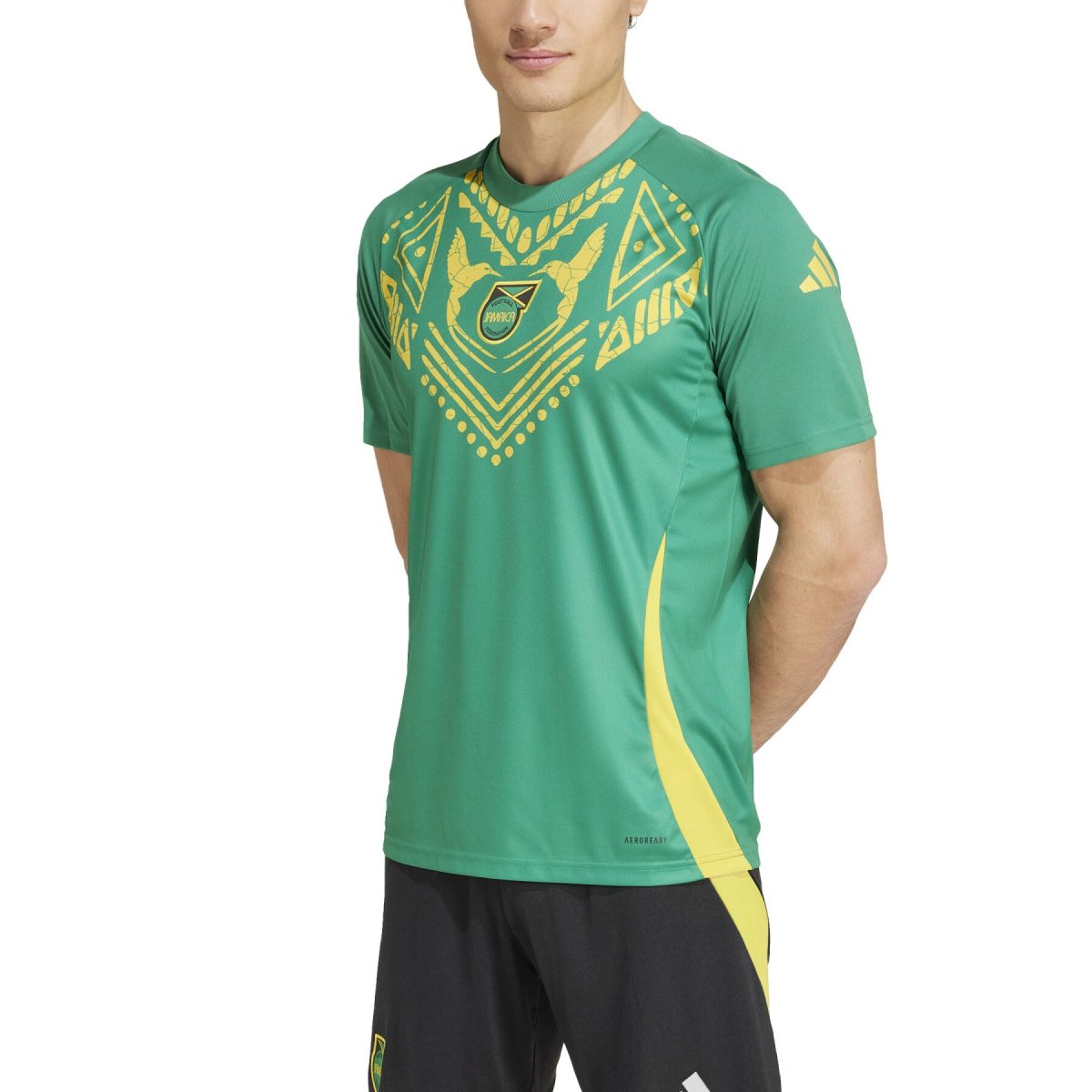 Athlete wearing a green training jersey with gold geometric pattern and Jamaica crest on the chest, plus a yellow side stripe.