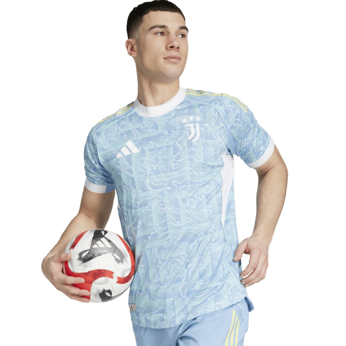 Young man in a light-blue patterned soccer jersey holding a red-and-white soccer ball against a white background.