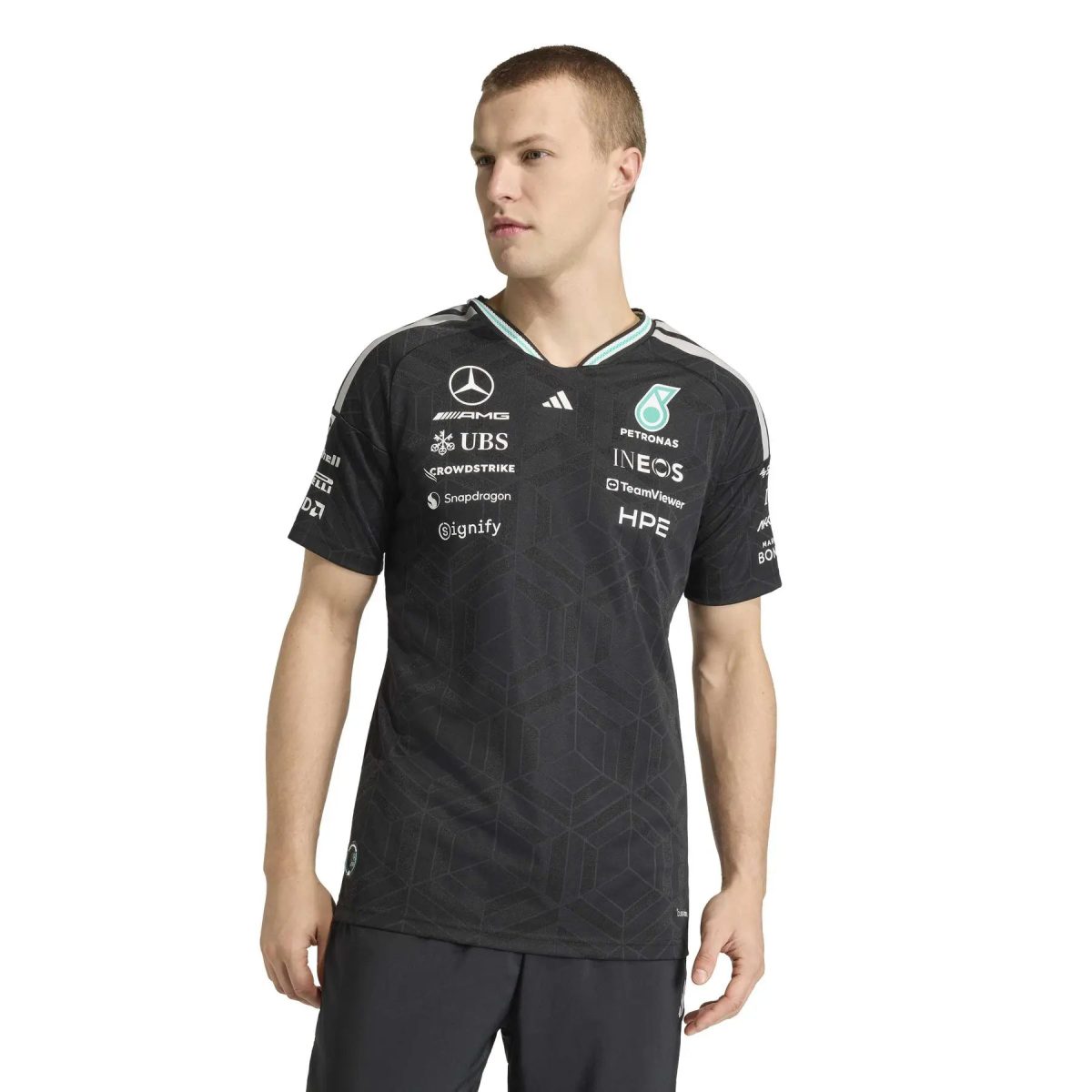 Male model wearing a black, patterned Mercedes‑AMG Petronas F1 team jersey with sponsor logos visible on the chest and sleeves (torso shot).