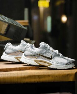 Pair of white and gray Nike running shoes displayed on a wooden counter in a store setting