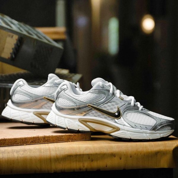 Pair of white and gray Nike running shoes displayed on a wooden counter in a store setting