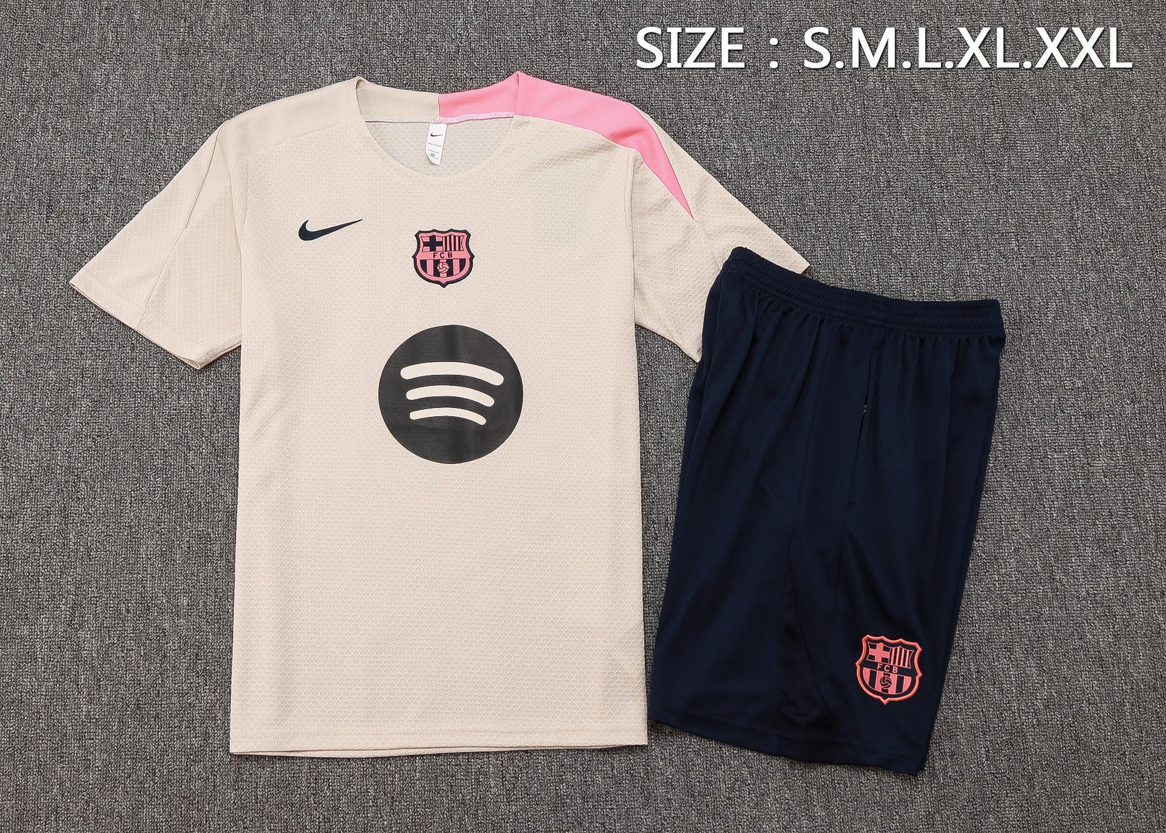 ae36c7dc | UAE SPORT STORE Beige FC Barcelona soccer jersey with pink shoulder detail, black Nike swoosh, club crest, and dark navy shorts with Barça emblem.