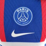 Close-up of the Paris Saint-Germain club badge on a blue jersey with red stripes and a white Nike swoosh nearby.