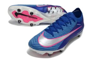 Blue Nike soccer cleats with pink swoosh, shown from side with studs visible on the sole (cleats for firm-ground play).