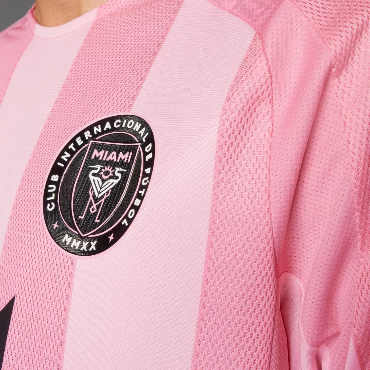Close-up of a pink sports jersey showing a black circular club badge with 'MIAMI' and 'MMXX' text on the chest area.