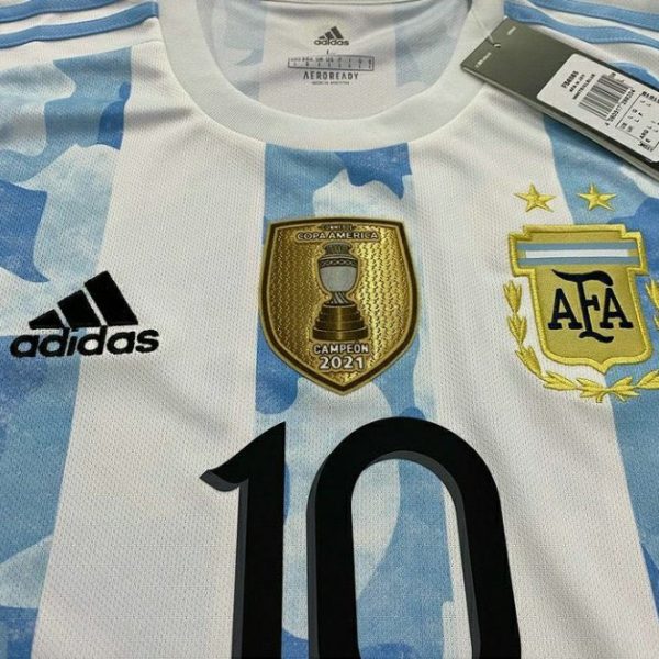 Chest close-up of the Argentina shirt with black 10 printing, AFA crest and CONMEBOL CAMPEÓN 2021 badge.
