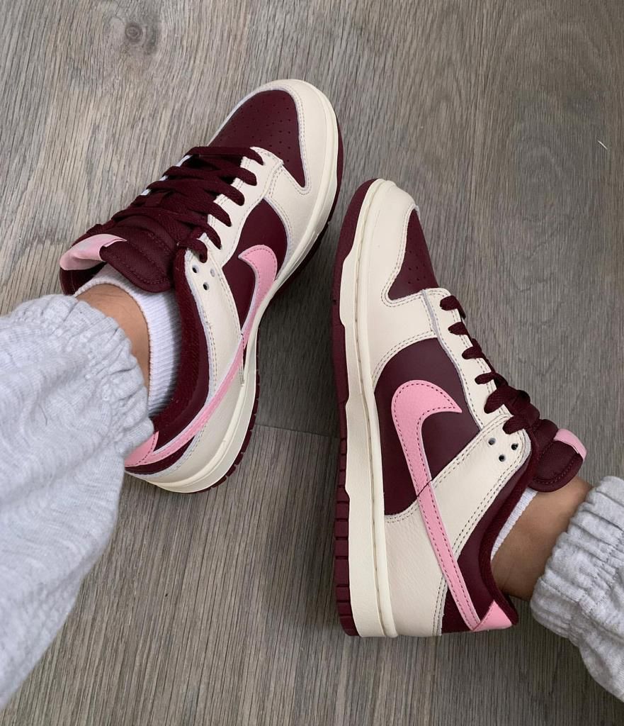 b0111e0d-cb09-4f3b-bb33-5ee69f1323d6 | UAE SPORT STORE Burgundy and pink Nike sneakers worn with white socks, seen from above on a wood floor.