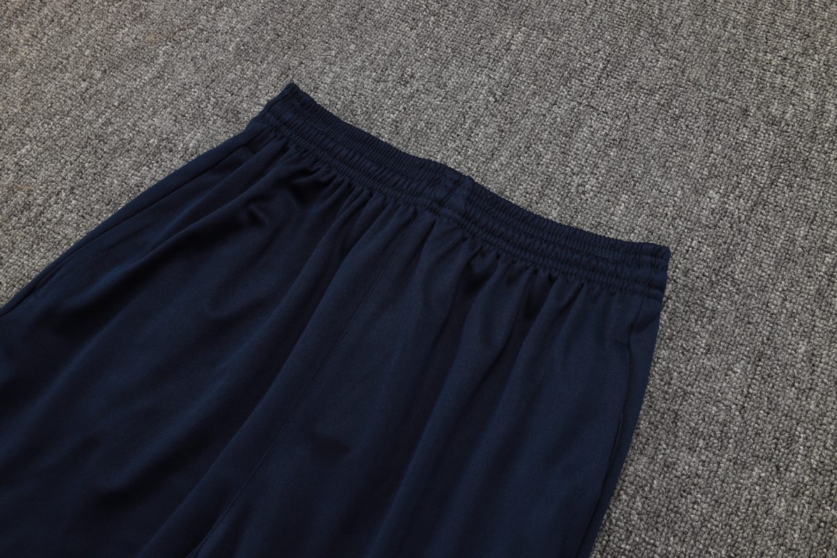 Navy blue elastic-waisted pants laid on a gray carpet, showing gathered waistband and soft fabric edge.