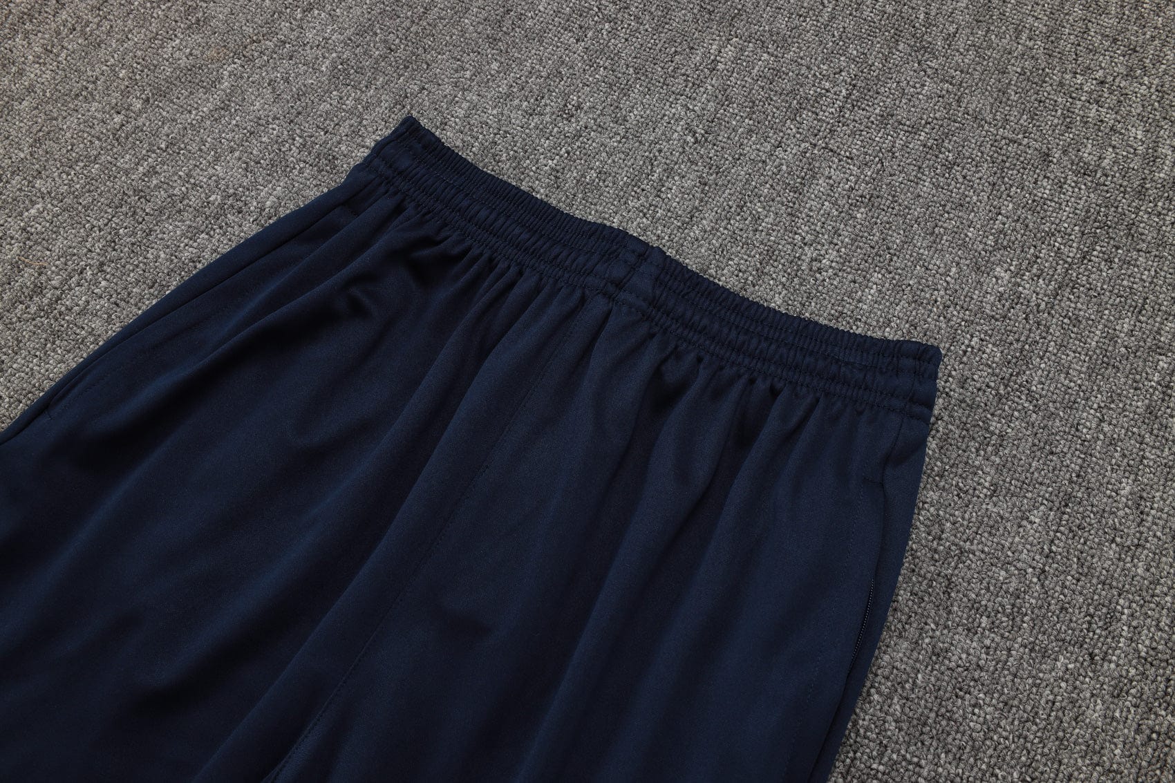 b050131e | UAE SPORT STORE Navy blue elastic-waisted pants laid on a gray carpet, showing gathered waistband and soft fabric edge.