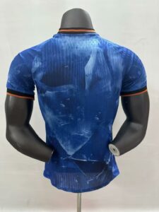 b07c0bbf | UAE SPORT STORE Back view of a blue athletic T-shirt on a mannequin, featuring orange and black trim at the collar and sleeve cuffs.
