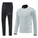 Nike black track pants with white swoosh logos paired with a light gray long-sleeve pullover featuring a black stand-up collar and white side panels.