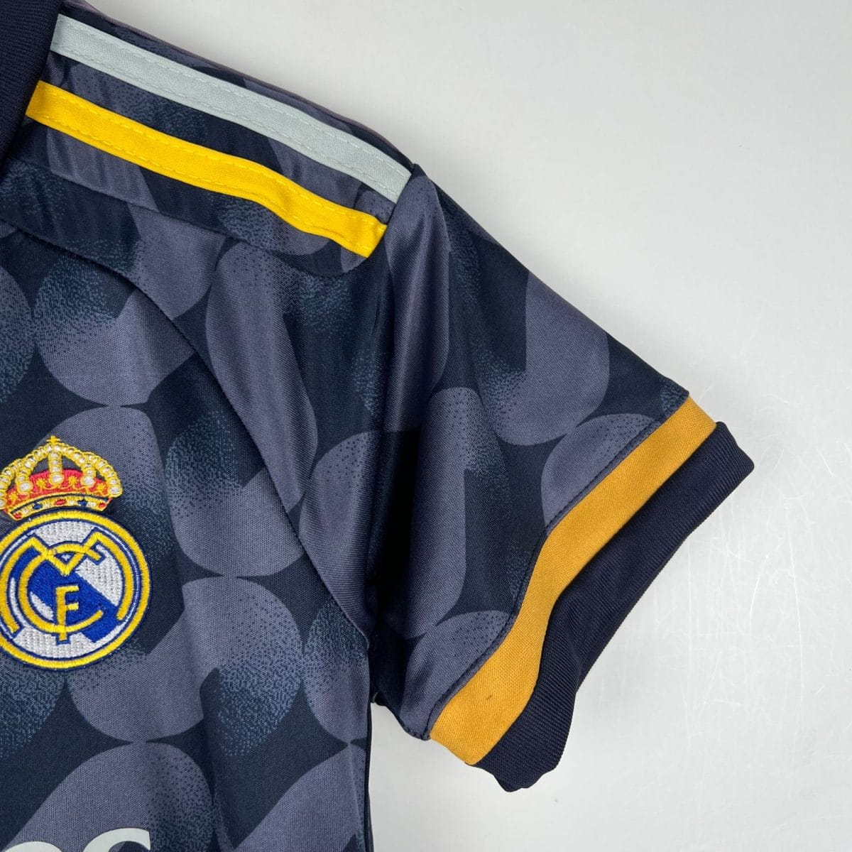 Close-up of a navy camouflage Real Madrid jersey sleeve with a bright yellow trim and club crest partially visible at the hem.