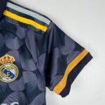 Close-up of a navy camouflage Real Madrid jersey sleeve with a bright yellow trim and club crest partially visible at the hem.