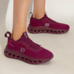Magenta athletic sneakers worn on feet, featuring a chunky hollow outsole and pull tabs at the heel and tongue.
