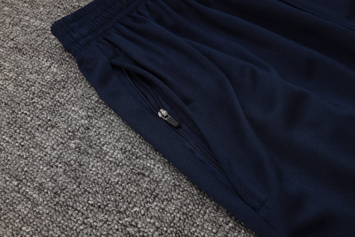 Close-up of navy blue fabric with a zipper along a seam, lying on a gray carpet.
