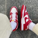 b1e84fac-c8a9-4bb6-bcb1-ba972d2a5282_39a1fddc-7c7b-414d-9da8-6f690d8b2754 | UAE SPORT STORE Person wearing red and white Nike sneakers with white socks standing on gray pavement.