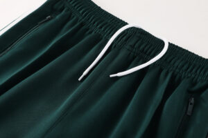 Dark green athletic shorts with a white drawstring and zippered pockets.