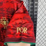 Close-up of a red Portugal jersey sleeve with gold 'POR' text and crest, hanging on a metal rack.