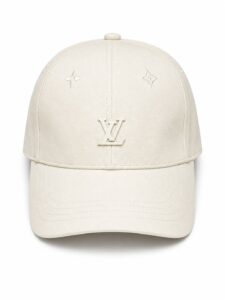 Beige Louis Vuitton baseball cap with an embossed LV logo on the front panel and small monogram marks on either side.