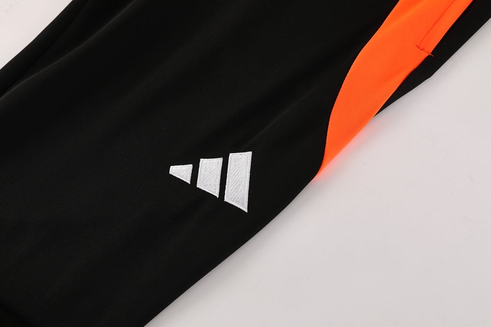 b2b6c5bf | UAE SPORT STORE Close-up of black fabric with a white Adidas logo and an orange side stripe.