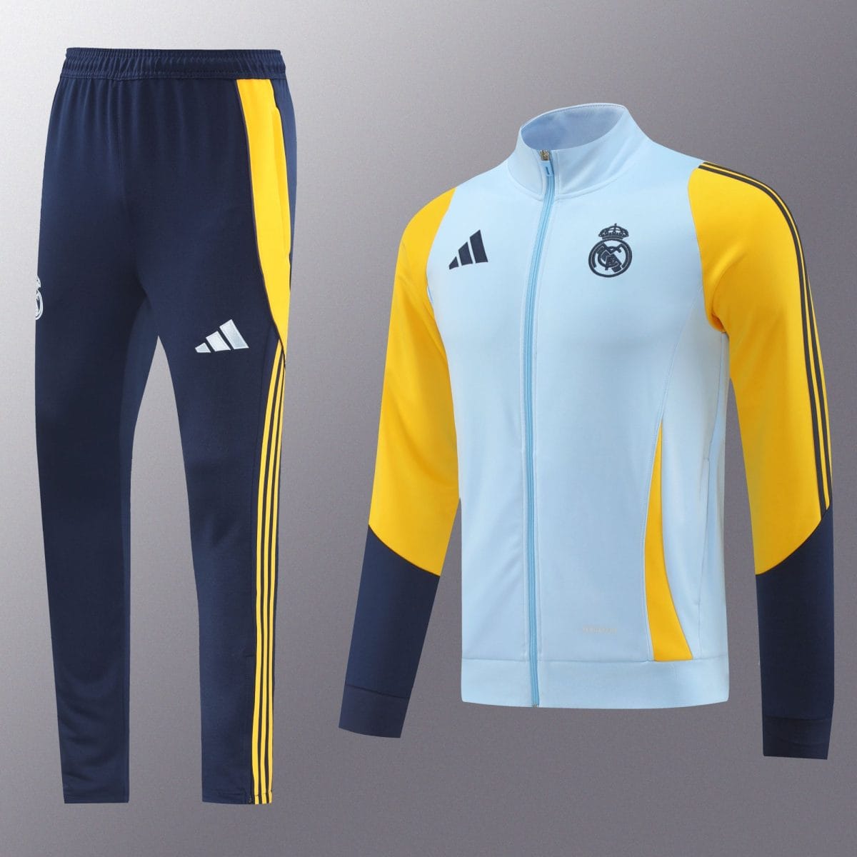 Navy track pants with yellow side stripes paired with a light blue and yellow Real Madrid jacket featuring the club crest and Adidas logo on the chest.