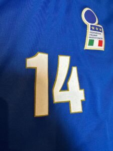 Blue soccer jersey with the number 14 and a badge reading Federazione Italiana Gioco Calcio, featuring the Italian flag colors in the top-right.