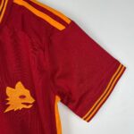 Close-up of a red sports jersey sleeve with orange trim and striped cuff.