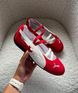 b57426cf-1ae5-45f1-b385-69d3f2f5168f | UAE SPORT STORE Red and white Puma baby sneakers with white straps, shown on a light carpet.