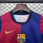 Close-up of a red and blue soccer jersey on a wooden hanger, with the FC Barcelona crest visible on the chest. Background shows a metal lattice fence.