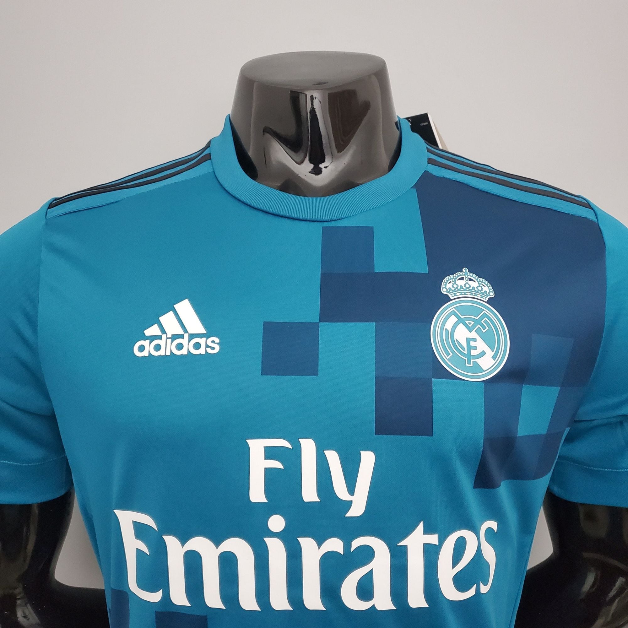 b5a32e7a_5b858866-56f3-45f4-bc1f-10ef2c31f9bc | UAE SPORT STORE Teal Real Madrid football jersey with Adidas logo and club crest, showing the 'Fly Emirates' sponsor text.