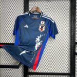 Blue Japan national football team jersey on a wooden hanger against a chain-link fence backdrop.