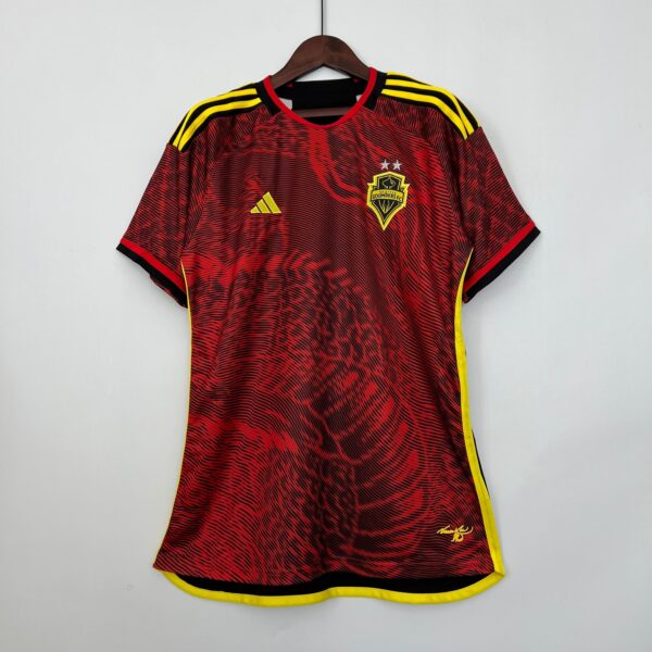 Red and black Seattle Sounders FC soccer jersey with yellow trim on a wooden hanger.