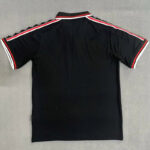 Back view of a black polo shirt with red and white racing stripes along the shoulders and sleeve edges.
