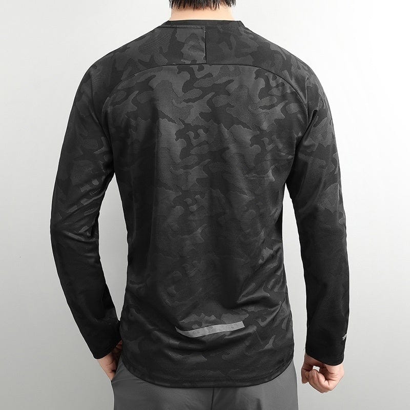 b7114917 | UAE SPORT STORE Back view of a person wearing a dark gray camouflage long-sleeve athletic shirt, standing against a light background. Includes a subtle reflective patch at the lower back.
