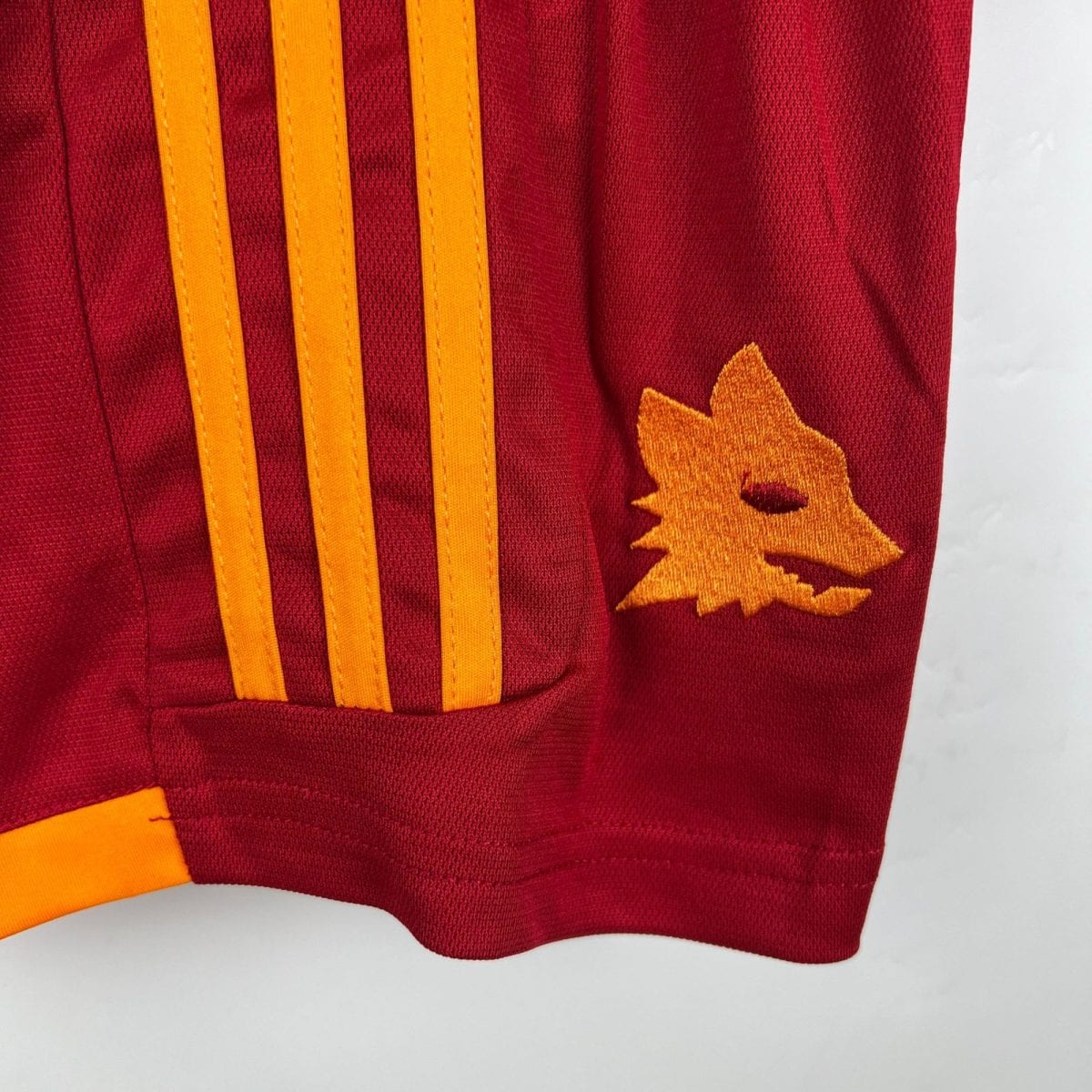 Close-up of maroon fabric with orange vertical straps and an orange star applique on the right side.