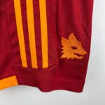 Close-up of maroon fabric with orange vertical straps and an orange star applique on the right side.