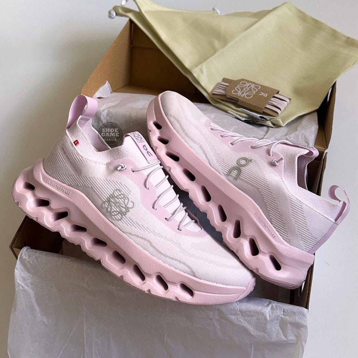 Pair of light pink athletic sneakers with a chunky sole in an open shoebox.