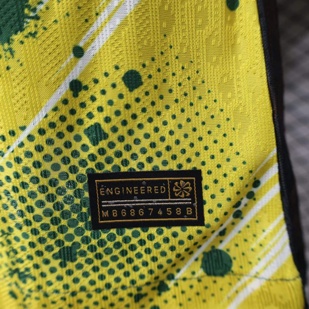 Close-up of high-visibility yellow fabric with green speckles and a black patch reading ENGINEERED.