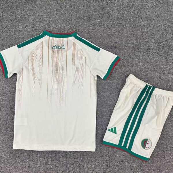 White soccer kit consisting of a short-sleeve jersey and matching shorts, with green and red trim and Arabic text on the back of the jersey; shorts have green stripes and a small circular emblem near the hem.
