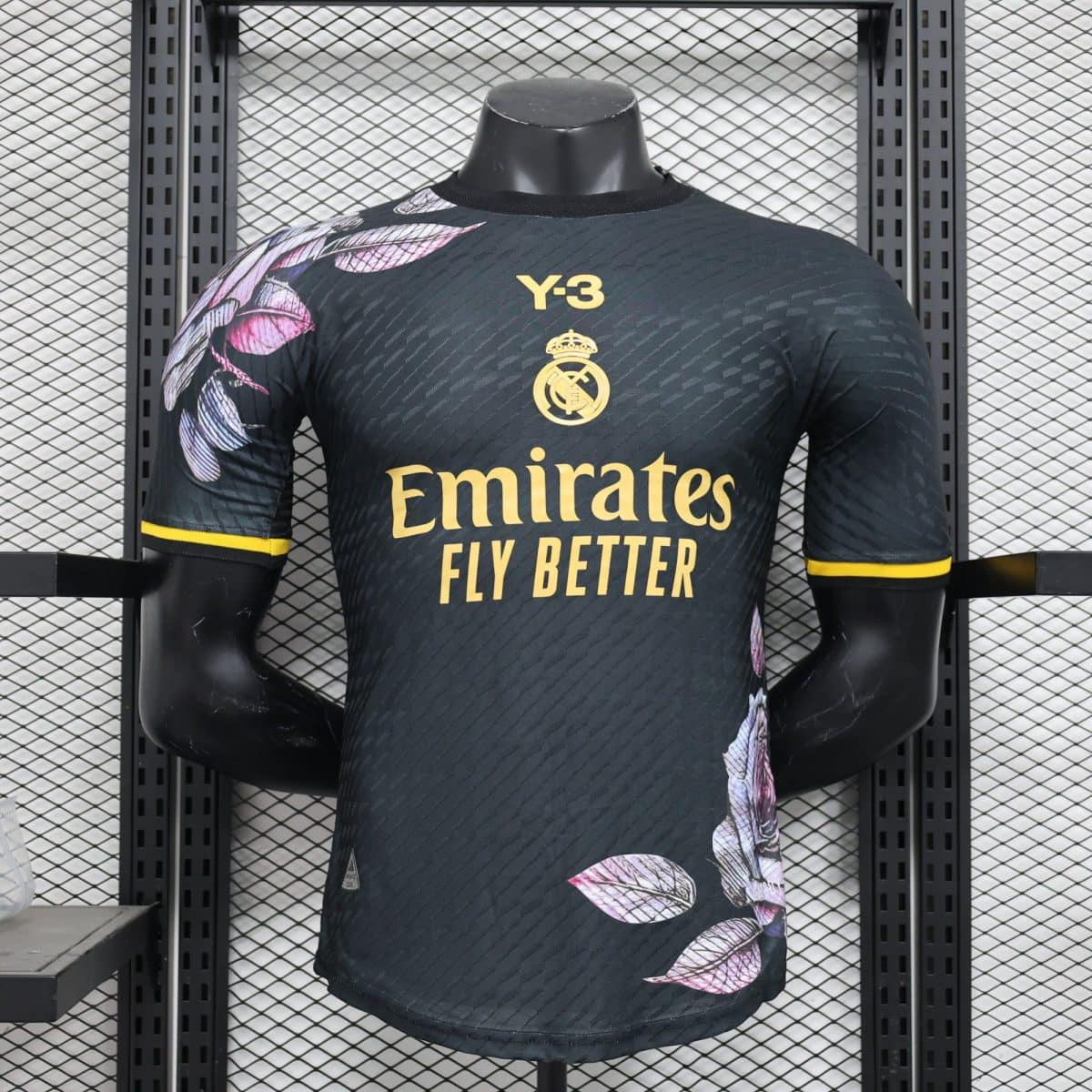 Mannequin wearing a Real Madrid football jersey with the yellow crest, Emirates Fly Better slogan, and a dark patterned fabric.