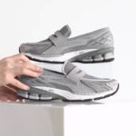 b9b359ae-a989-48c9-b040-0a82b3a90ec2 | UAE SPORT STORE Pair of gray athletic sneakers with Velcro straps and visible cushioning, placed on a white surface.