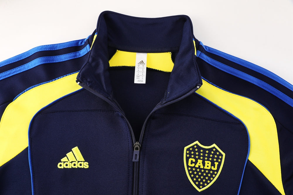 b9efe665 | UAE SPORT STORE Navy Adidas tracksuit jacket with yellow panels and a CABJ crest on the chest, zipper front, blue stripes along shoulders.