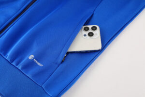 ba125a3e | UAE SPORT STORE Blue athletic jacket pocket with a smartphone partially tucked inside, zipper visible on the side.