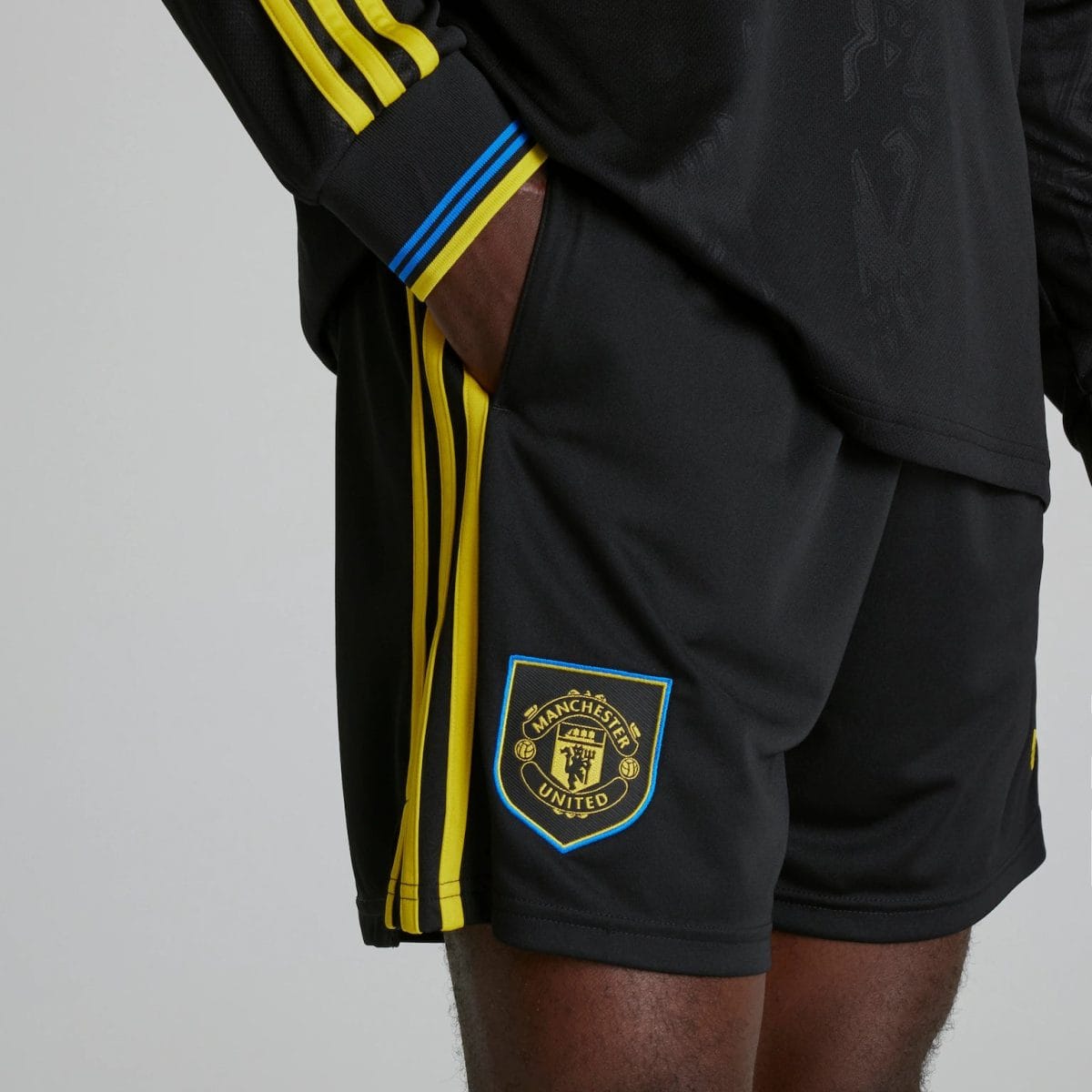 Black Manchester United shorts with yellow side stripes and club crest on the leg area