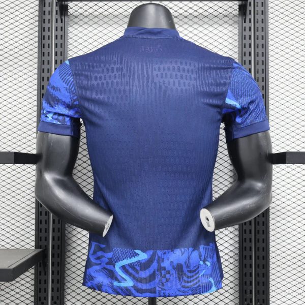 Back view of a blue athletic jersey on a mannequin, showing perforated fabric and geometric patterns at the bottom hem.