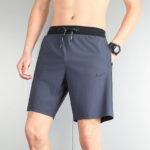 Male model wearing dark gray Nike athletic shorts with a black elastic waistband and drawstring.