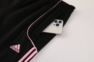 bac4ab3c | UAE SPORT STORE Black Adidas track pants with pink piping; a smartphone sticks out of the back pocket.
