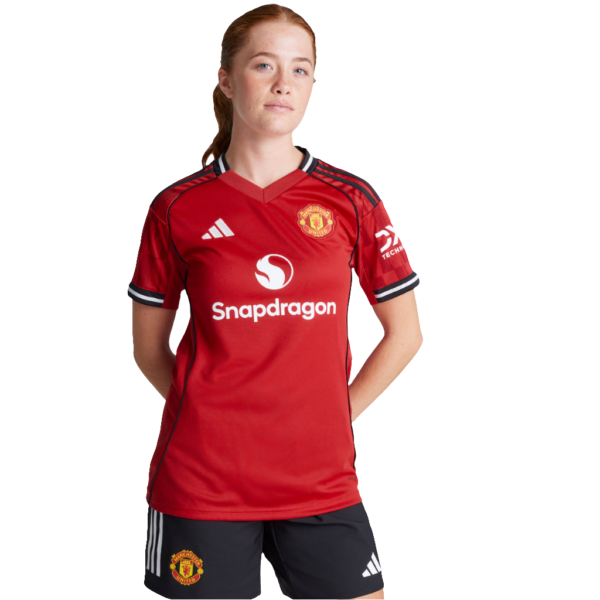 Female footballer in a red Manchester United jersey with Snapdragon sponsor, standing with hands behind her back.